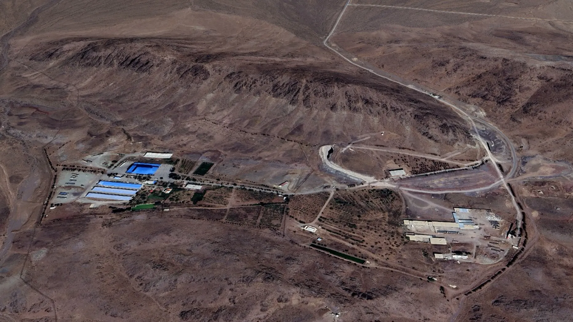 Satellite imagery shows the Shahid Soltani Garrison, outside of Eshtehard City, Iran, including large storage warehouses (left), a set of smaller buildings (right) and an underground tunnel with two openings (center). (NCRI/MEK)